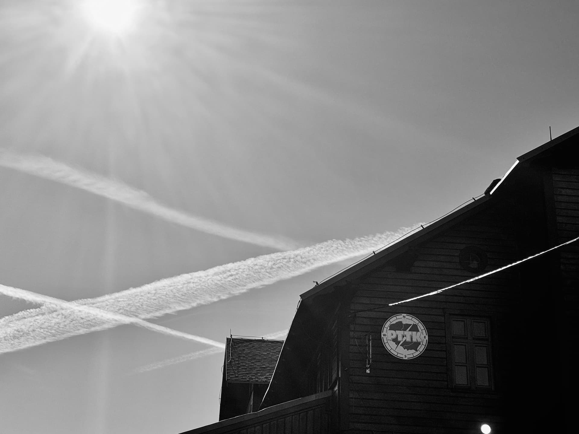 PTTK mountain shelter on Śnieżnik peak with contrails crossing the sky